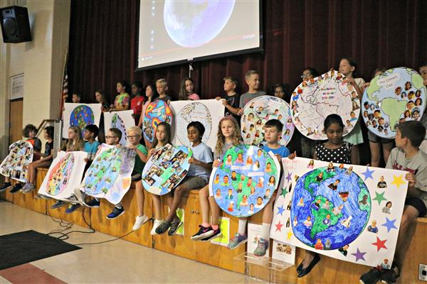 Students display the globes they made that have a picture of each member of each class. 